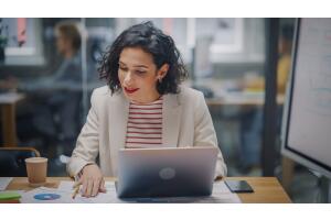 Mulher em uma mesa de trabalho com notebook na frente.