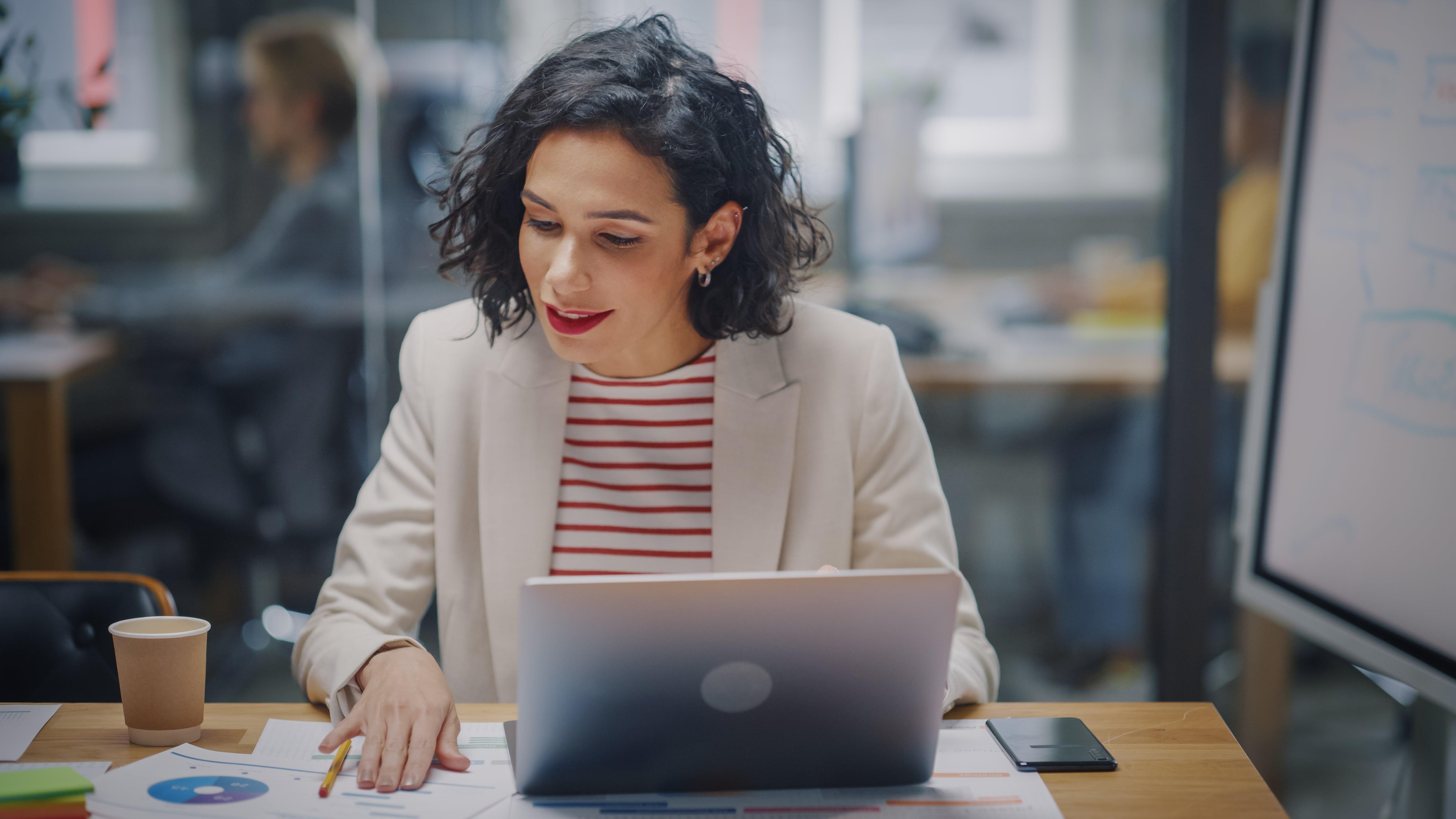 Mulher em uma mesa de trabalho com notebook na frente.