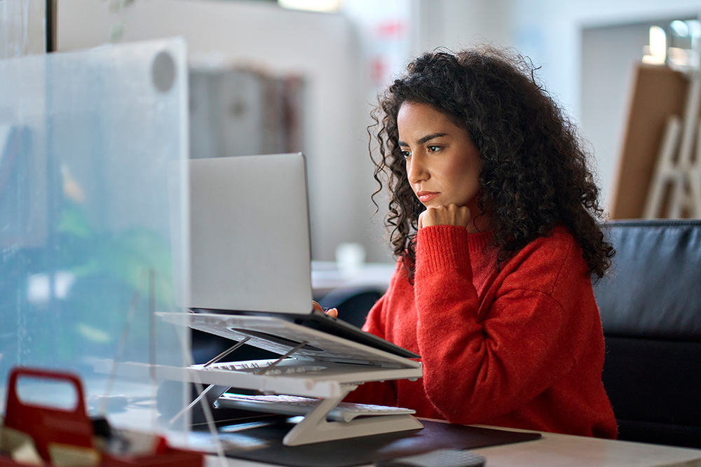 uma mulher de cabelos encaracolados olhando atentamente para o computador