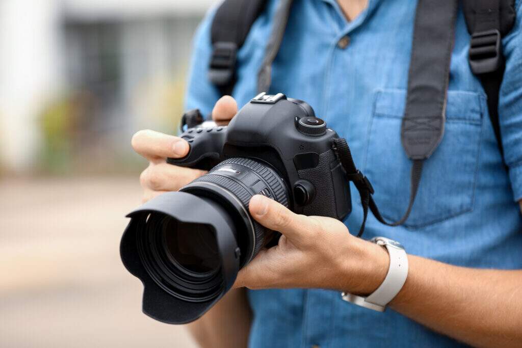 Pessoa segurando uma câmera fotográfica profissional, representando uma das maiores invenções feitas no Brasil.
