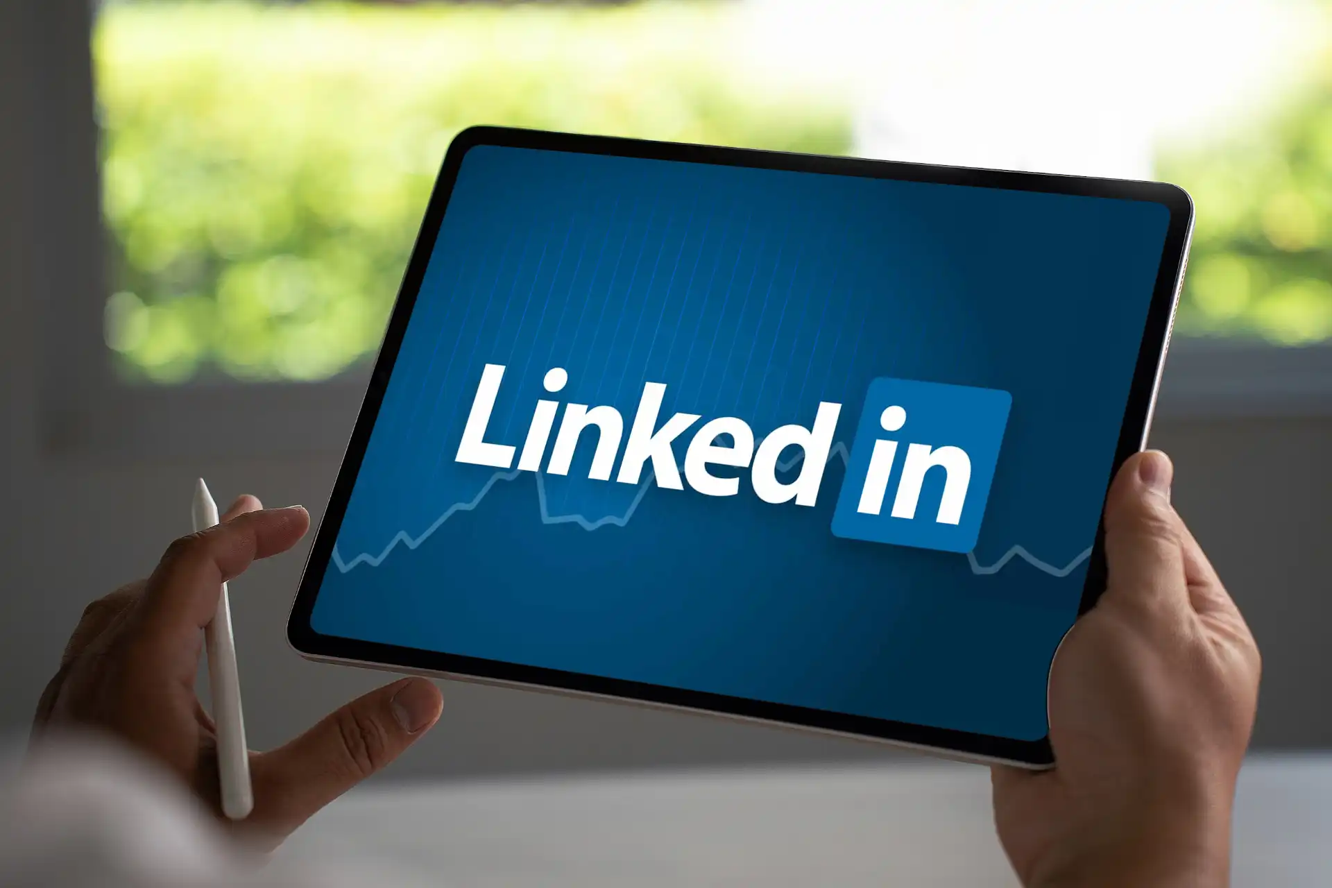 profissional usando o LinkedIn em tablet, representando como usar o LinkedIn para conseguir emprego e otimizar perfil no LinkedIn