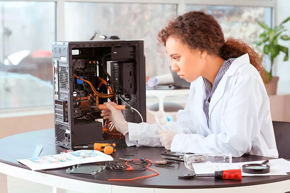 Profissional realizando montagem e manutenção de computadores durante diagnóstico e reparo de componentes de hardware.