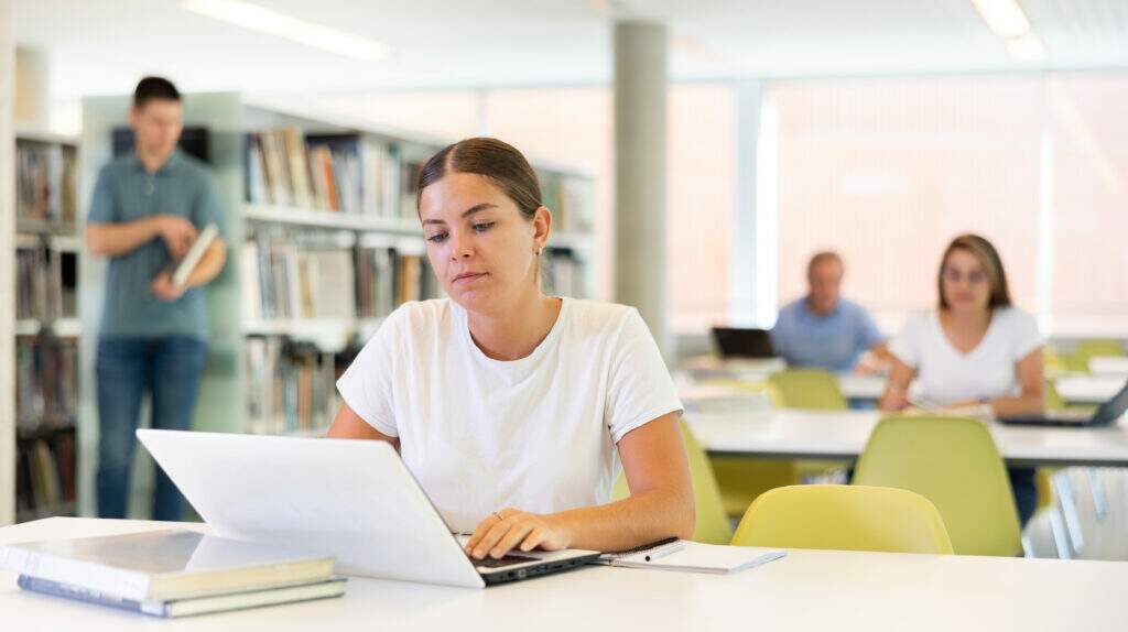 Jovem pensativa enquanto faz um teste vocacional gratuito no notebook, ambiente leve e acolhedor.