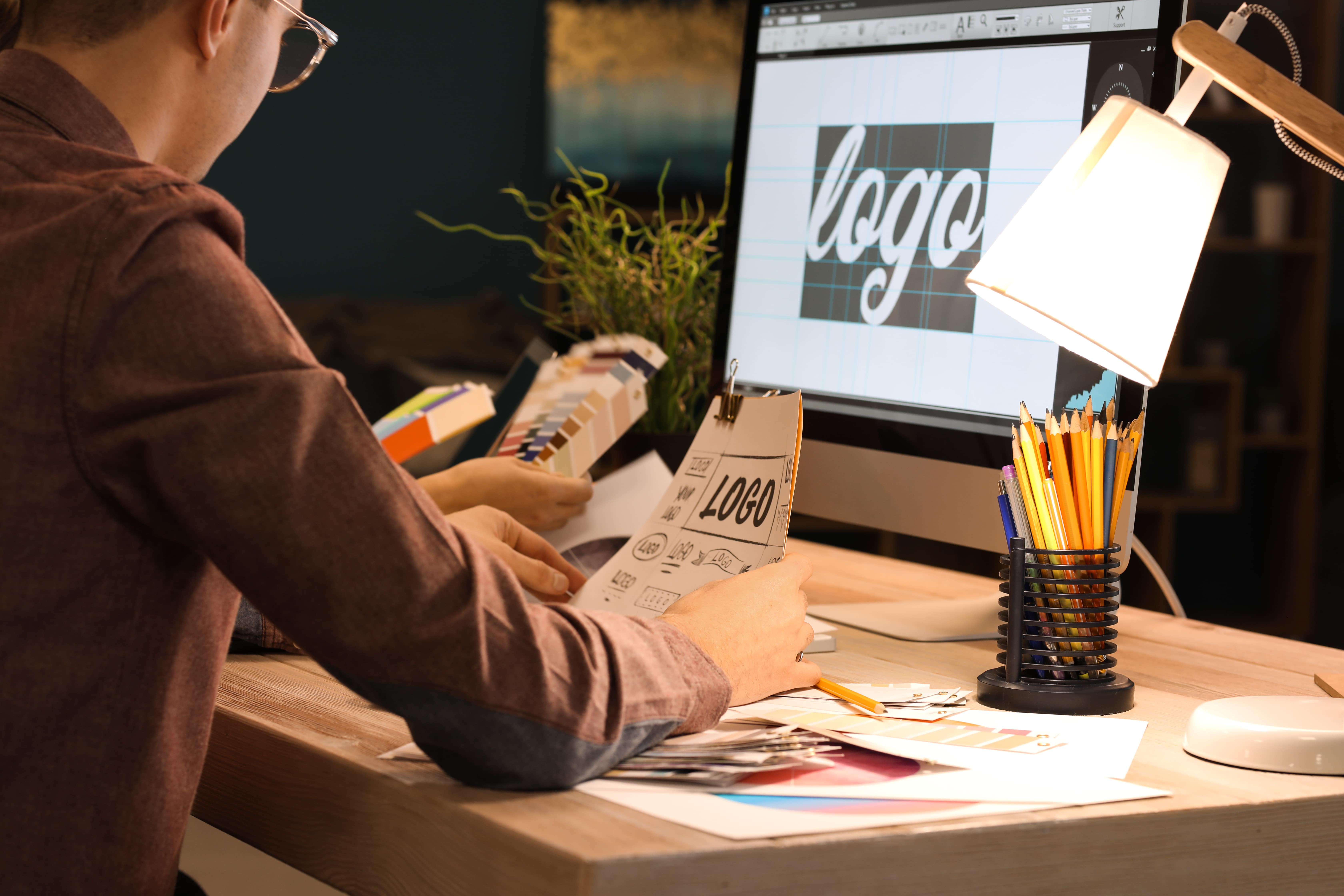 Jovem trabalhando na cria&ccedil;&atilde;o de identidade visual em computador, representando como o design gr&aacute;fico &eacute; destaque nos cursos para ganhar dinheiro desde cedo