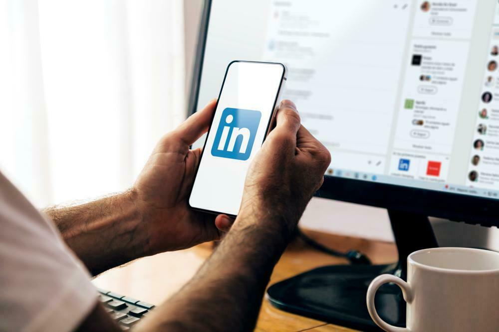 Jovem usando o aplicativo do LinkedIn no celular para atualizar o perfil profissional, se preparando para entrevista de emprego mesmo sem experiência.