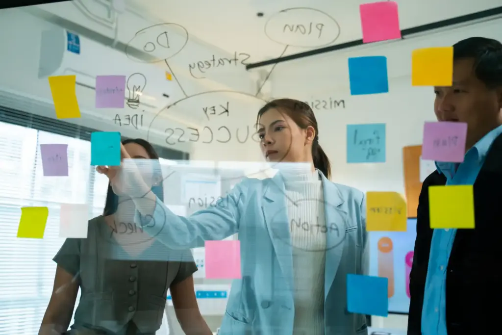 Equipe de profissionais discutindo ideias relacionadas à economia criativa em uma reunião, utilizando post-its.