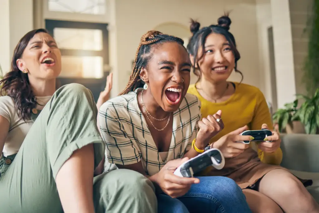 Três mulheres jovens jogando videogame e se divertindo, ilustrando o conceito de gamificação na educação de forma interativa e divertida.