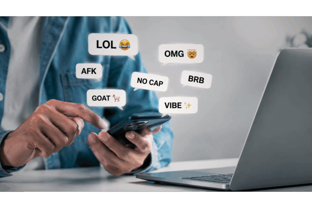 Mãos segurando celular com balões de chat mostrando gírias em inglês 
como LOL, OMG, AFK, NO CAP e GOAT — exemplos das 30 gírias em inglês 
mais usadas com tradução e pronúncia