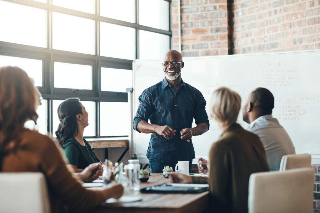 como desenvolver liderança no trabalho com equipe em reunião e gestor conduzindo pessoas