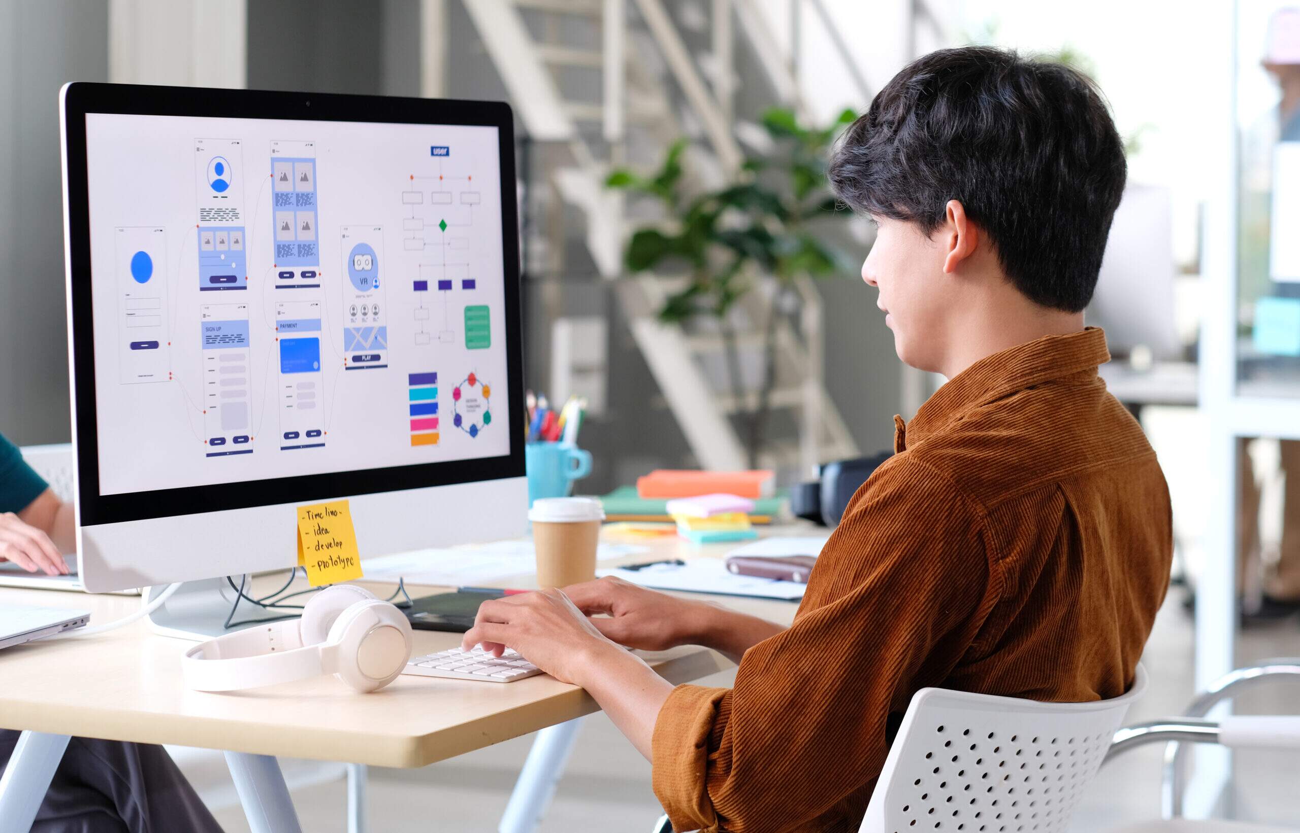 : Jovem estudando curso de web design no computador, aprendendo design de interfaces e criação de sites.