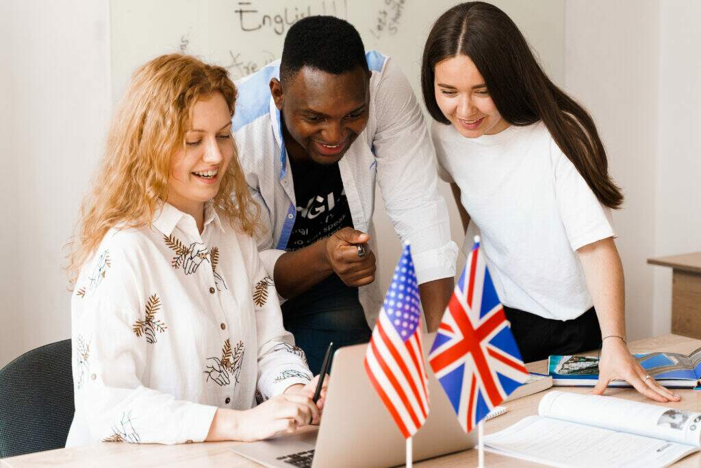 Estudante aprendendo past continuous em inglês com caderno de exercícios e gramática aberta sobre a mesa.