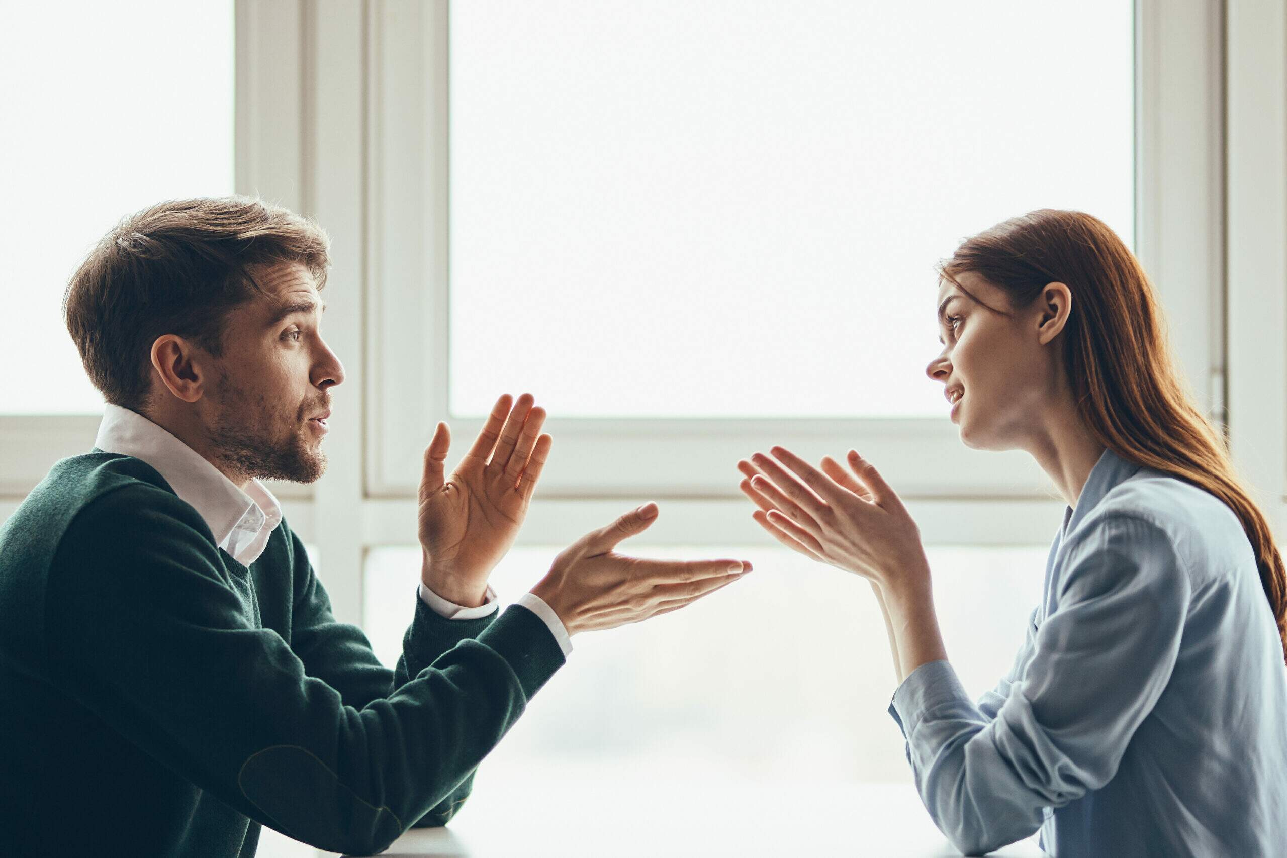 Dois colegas de trabalho conversando de forma atenta durante uma reunião, com contato visual e postura aberta — comunicação interpessoal