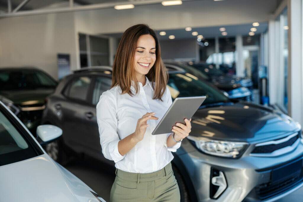 Técnicas de vendas: profissional utilizando tablet para consultar informações e atender clientes em uma concessionária de veículos.