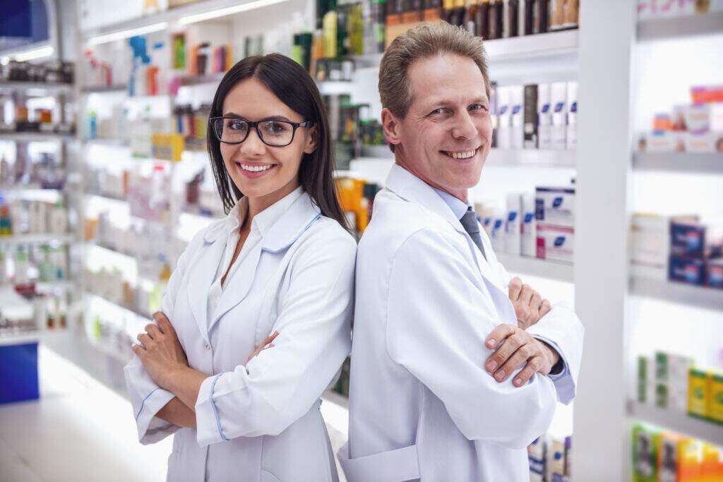 Técnico em farmácia orientando cliente sobre medicamentos em uma farmácia, com atendimento farmacêutico personalizado.
